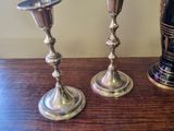two silver candlesticks sitting on a table next to a bottle of wine