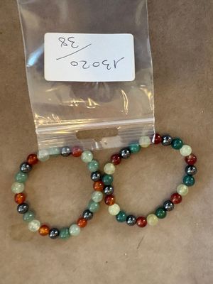 deux bracelets composés de perles vertes, rouges et noires, dans un sachet