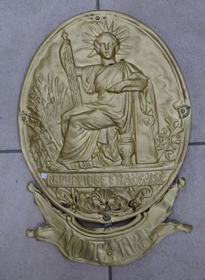 statue d'une femme tenant un bâton, représentée sur une plaque posée sur un sol carrelé