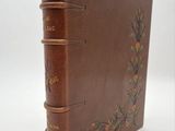 un vieux livre en cuir marron dont la couverture est ornée d'un motif floral