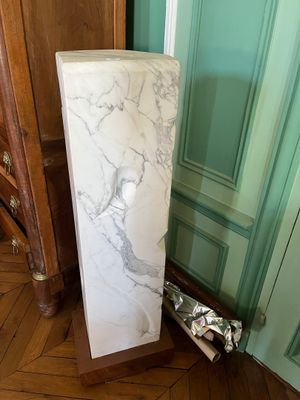 un socle en marbre dans un coin de la pièce, près d'une porte
