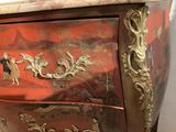 a red and gold chest of drawers with a clock on it