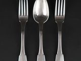 three forks and a spoon on a black surface