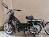 une petite moto noire garée contre un mur
