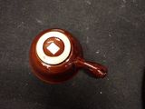 a brown cup with a brown handle sitting on a table
