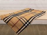plaid blanket on a wooden bench in front of a white wall
