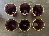 six purple glass cups sitting on top of a wooden table