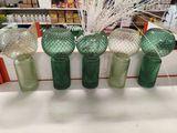 quatre vases en verre vert sont alignés sur une étagère
