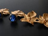 two pairs of gold and blue crystal earrings on a black surface