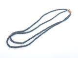 un gros plan d'un long collier de perles posé sur une surface blanche