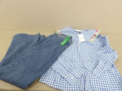 une chemise à carreaux bleus et blancs et un jean posés sur une table