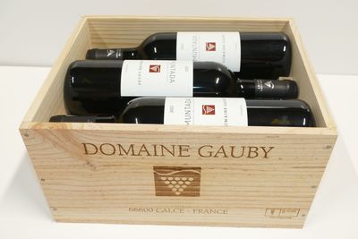 quatre bouteilles de vin dans un coffret en bois posé sur une table