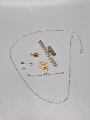 un collier en argent avec une chaîne en or et d'autres objets posés sur la table