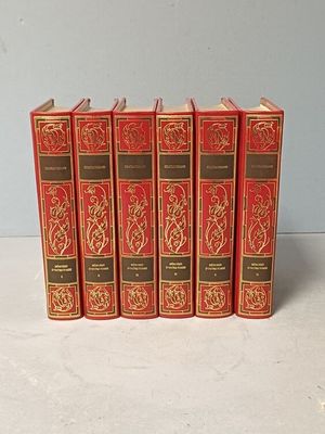 six livres rouges alignés sur une surface blanche