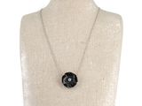 the necklace is on a mannequin with a black flower on it