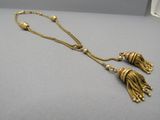 a close up of a gold necklace with tassels on a table