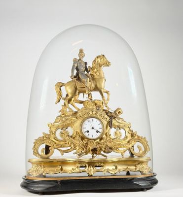 une horloge en or représentant un homme à cheval sous un dôme en verre
