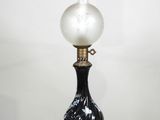 une lampe noire et blanche posée sur une table en bois près d'un mur blanc