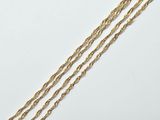 a close up of a gold necklace with a chain on a white surface