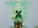 two green glass vases with green leaves on them on a table