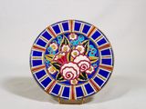 une assiette bleue décorée de fleurs, posée sur un socle
