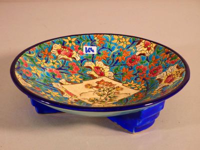a blue bowl with a design on it sitting on a stand