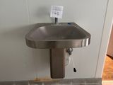 un lavabo dans un coin de la salle de bains, avec un distributeur de papier accroché au mur
