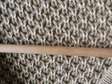knitted sweater with a wooden knitting needle on a wooden table