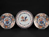 three plates with flowers and birds on them on a black surface