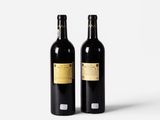 two bottles of wine sitting next to each other on a white surface