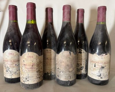 six bottles of red wine are lined up on a table