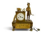 a gold clock with a man standing next to it