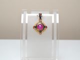 purple stone pendant on display in clear acrylic display case
