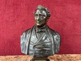 un buste en bronze représentant un homme assis sur une table en marbre