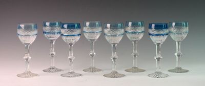 twelve wine glasses lined up in a row on a white surface