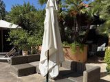 tables and chairs with umbrellas on a patio with palm trees in the background