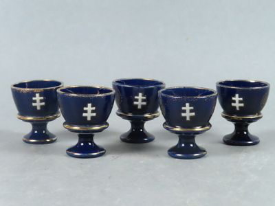 six verres bleus ornés de croix, posés sur une table