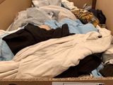 a cardboard box filled with clothes and a pile of clothes