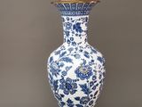 un vase bleu et blanc sur lequel est posée une lampe dorée