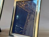 two silver picture frames sitting next to each other on a table