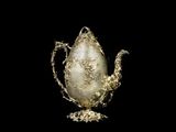 an image of a silver teapot on a stand with a black background