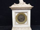 une petite horloge blanche surmontée d'un oiseau