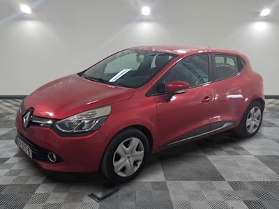 une voiture rouge est garée dans une pièce au sol en damier
