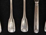 four forks and a knife are lined up on a black surface