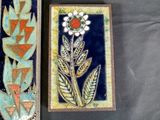 two decorative tiles with flowers on them on a table