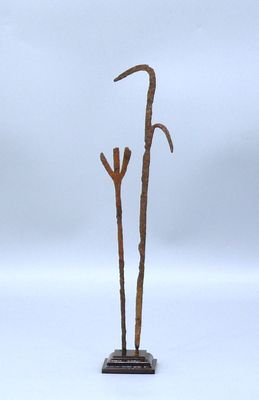une sculpture métallique représentant une plante, posée sur un socle en bois