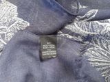 the label is on the back of a blue shirt with white flowers on it