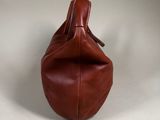 brown leather handbag on a white surface with a white background