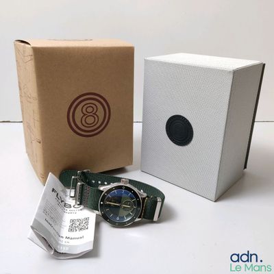 une photo d'une montre posée à côté d'une boîte en carton sur une table