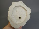 quelqu'un tient un vase blanc percé d'un trou au milieu